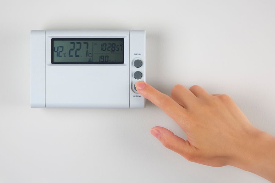 Tips to Troubleshoot Your Thermostat. Image of person pushing button on thermostat.