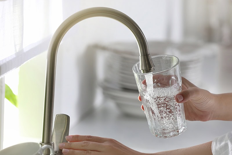 Is Your Family Exposed to "Forever Chemicals”? Photo of someone filling a glass of water from the kitchen sink faucet.